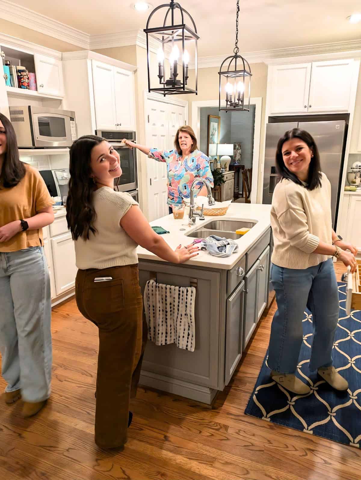 4 women cooking in a kitchen with white cabinets