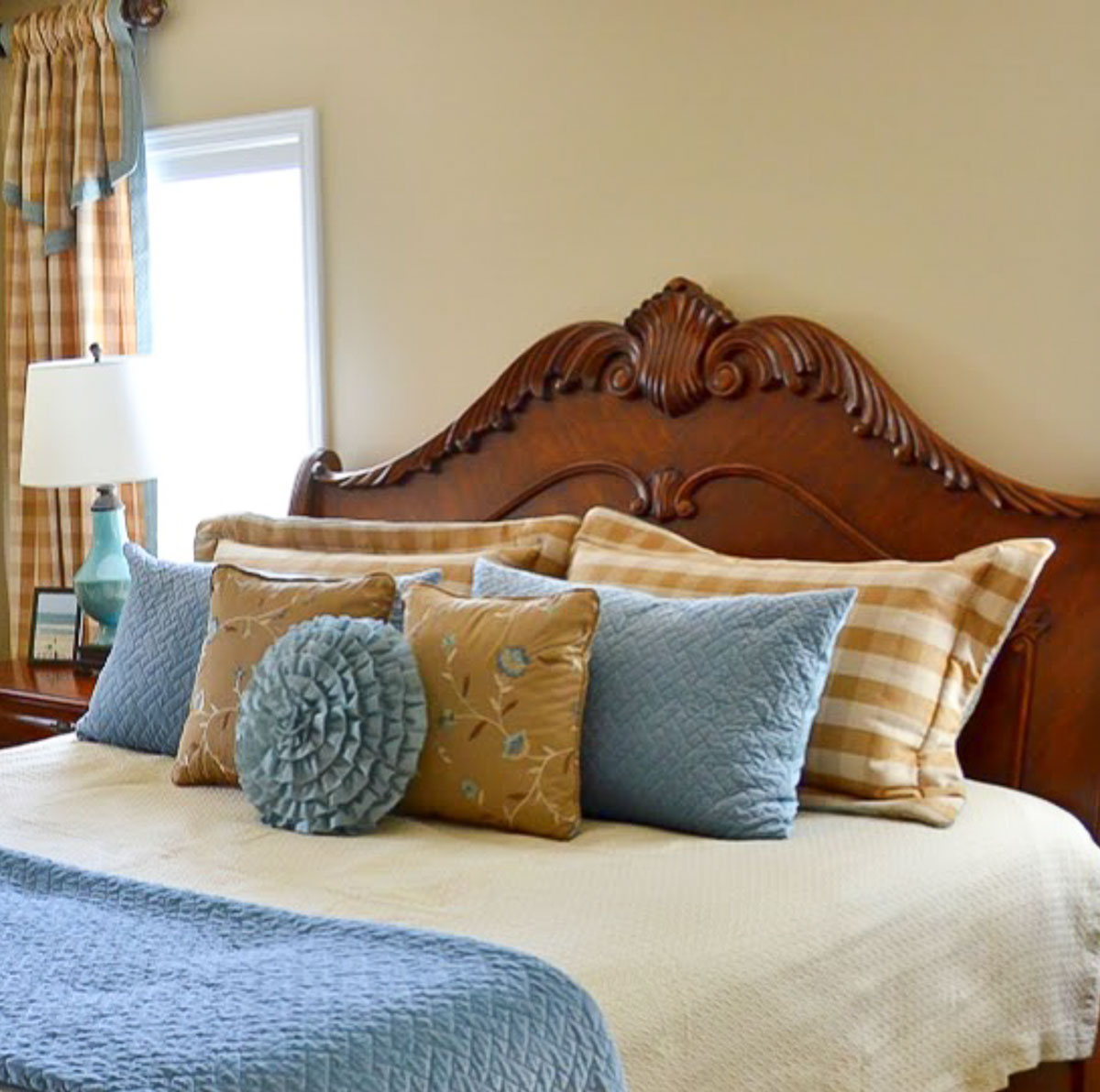 brown, cream and blue bed pillows and throw pillows on a king size bed with a wood headboard