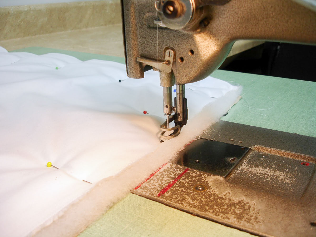 fabric and batting for a pillow sham pinned together at a sewing machine