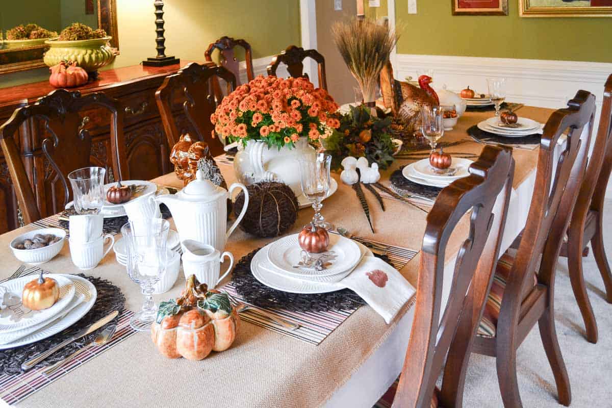 Thanksgiving tablescape with neutral linens, white dishes, and fall colored accents