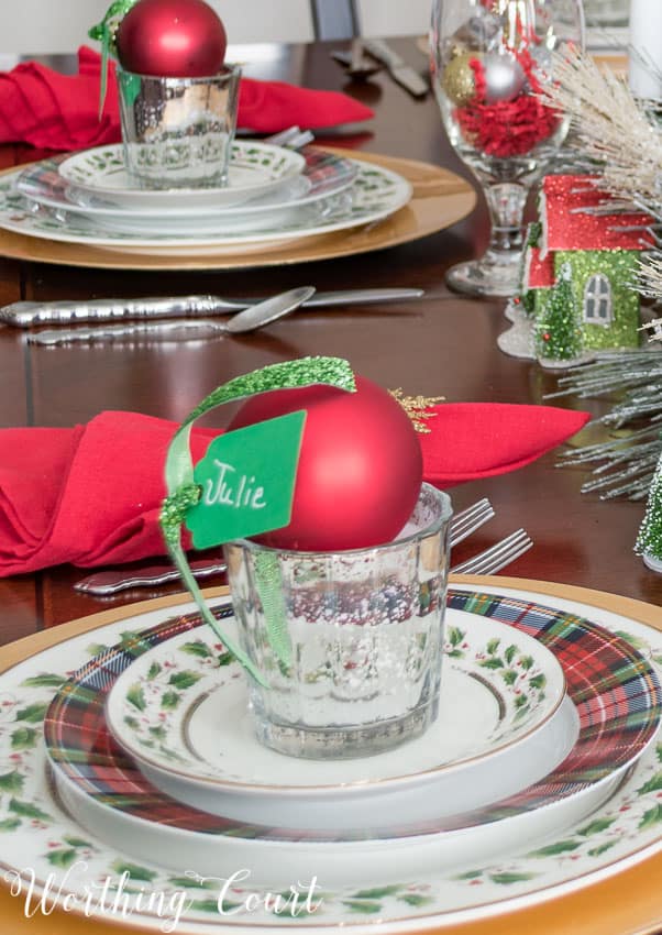 A red Christmas ornament holds the place setting card.