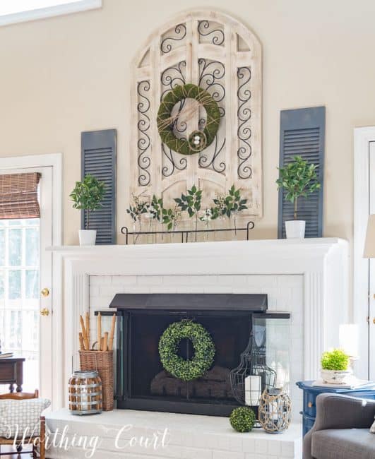 Red brick fireplace and oak mantel and surround painted white, brass firescreen painted with high temp black spray paint, large wood and metal arch window wall decor, spring fireplace decor