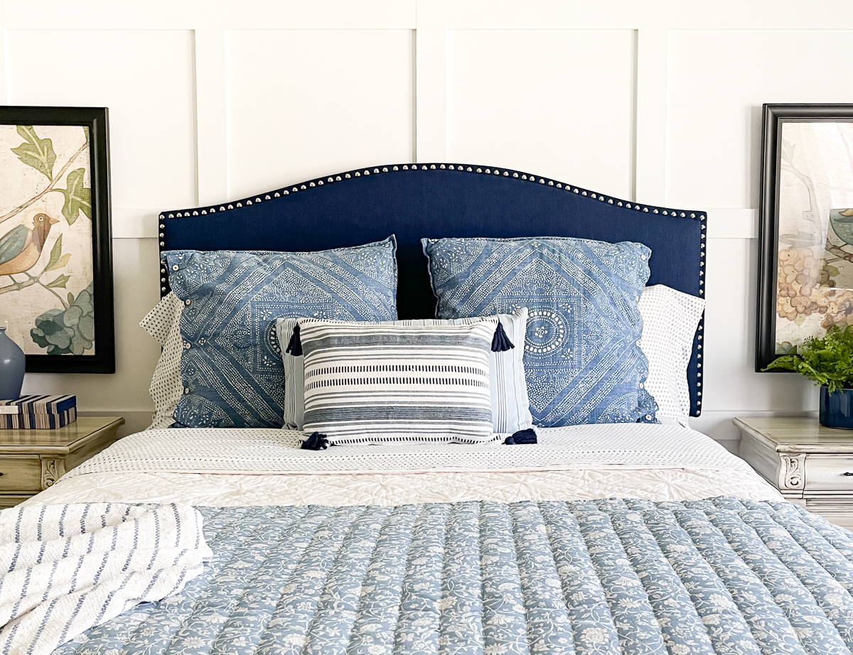 cottage style budget bedroom makeover with a navy blue upholstered headboard, board and batten feature wall, diy painted furniture and cottage style accessories