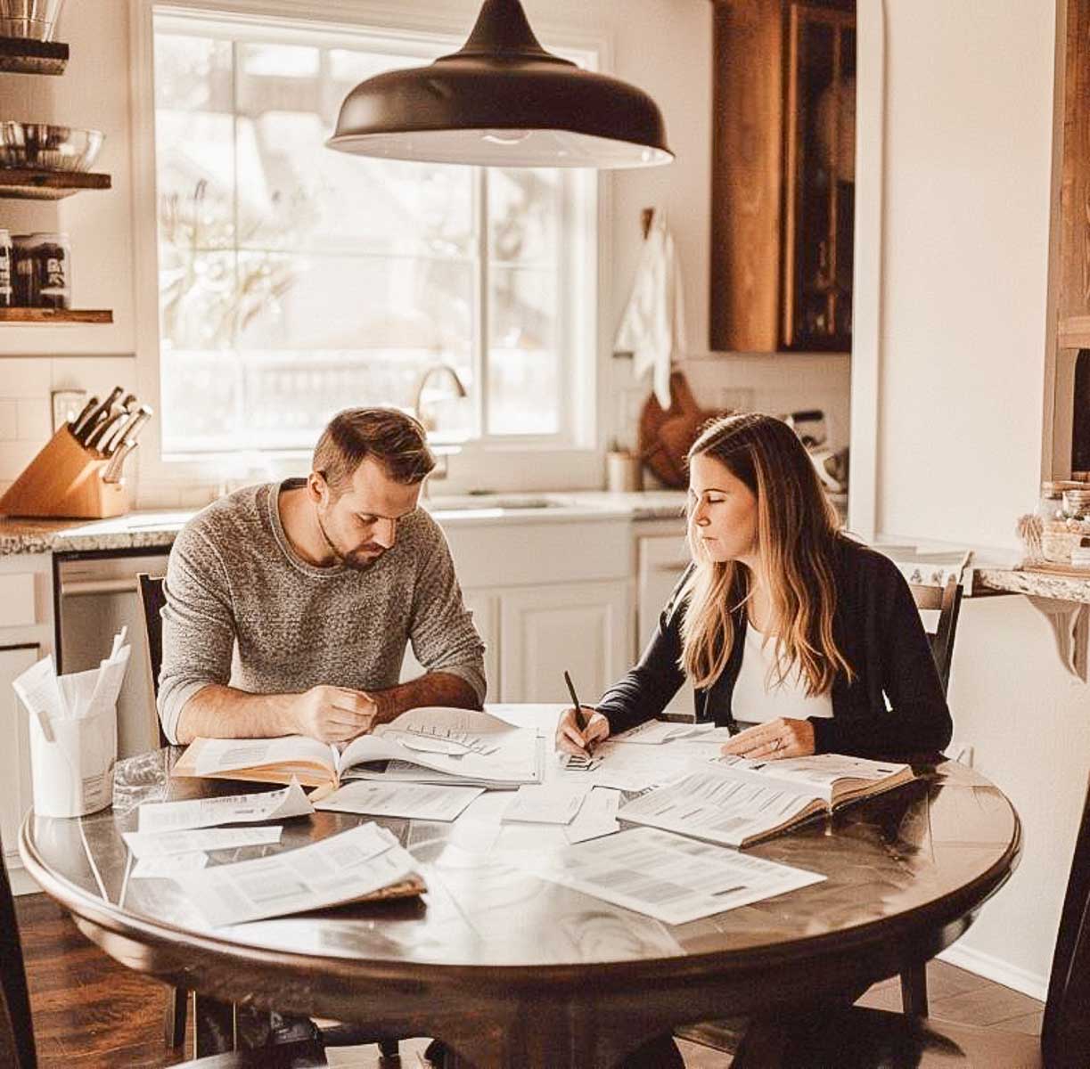 man and woman couple sitting at a round kitchen table going over their budget