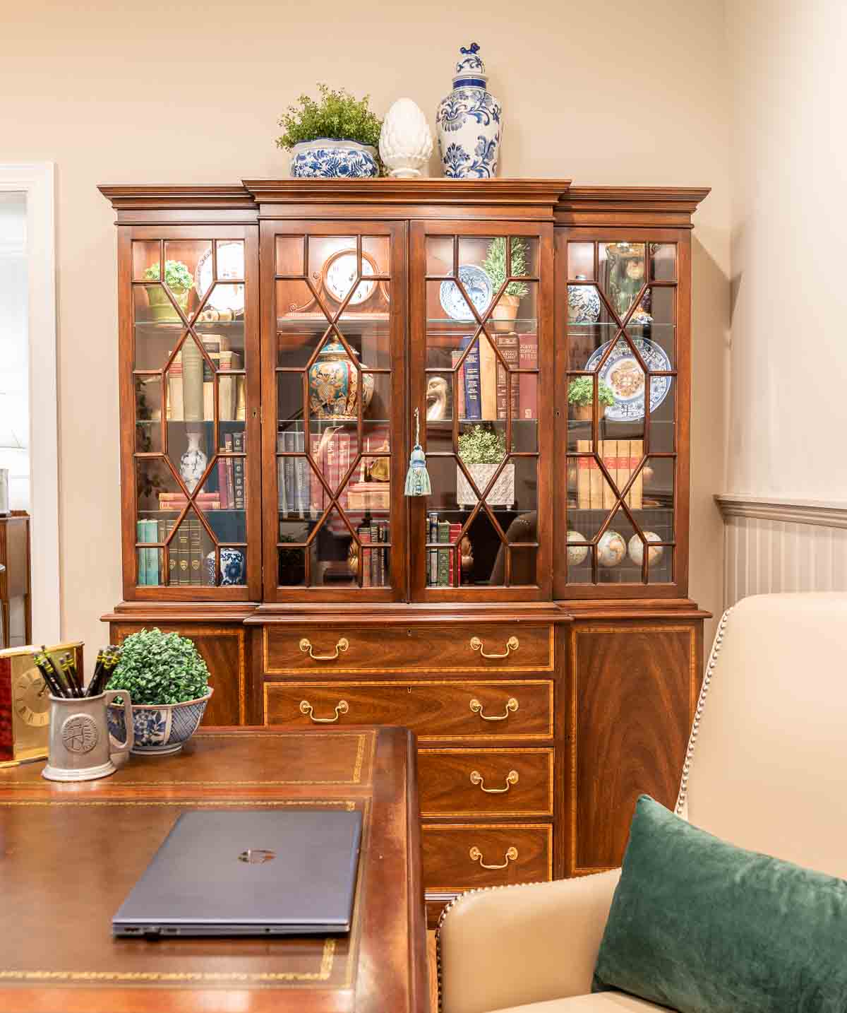 a traditional china hutch in a home office filled with traditional decorative objects and books
