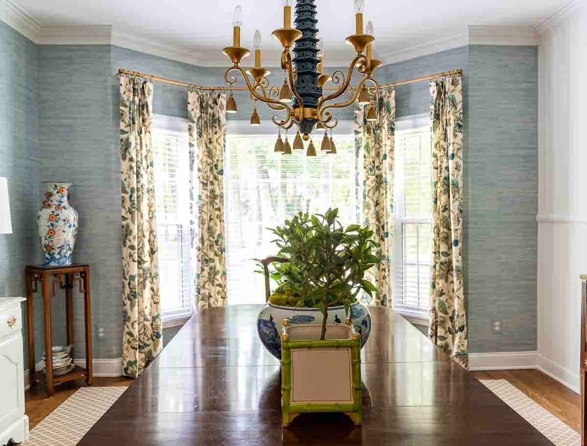 traditional style pleated draperies in the bay window of a dining room with blue grasscloth wallpaper