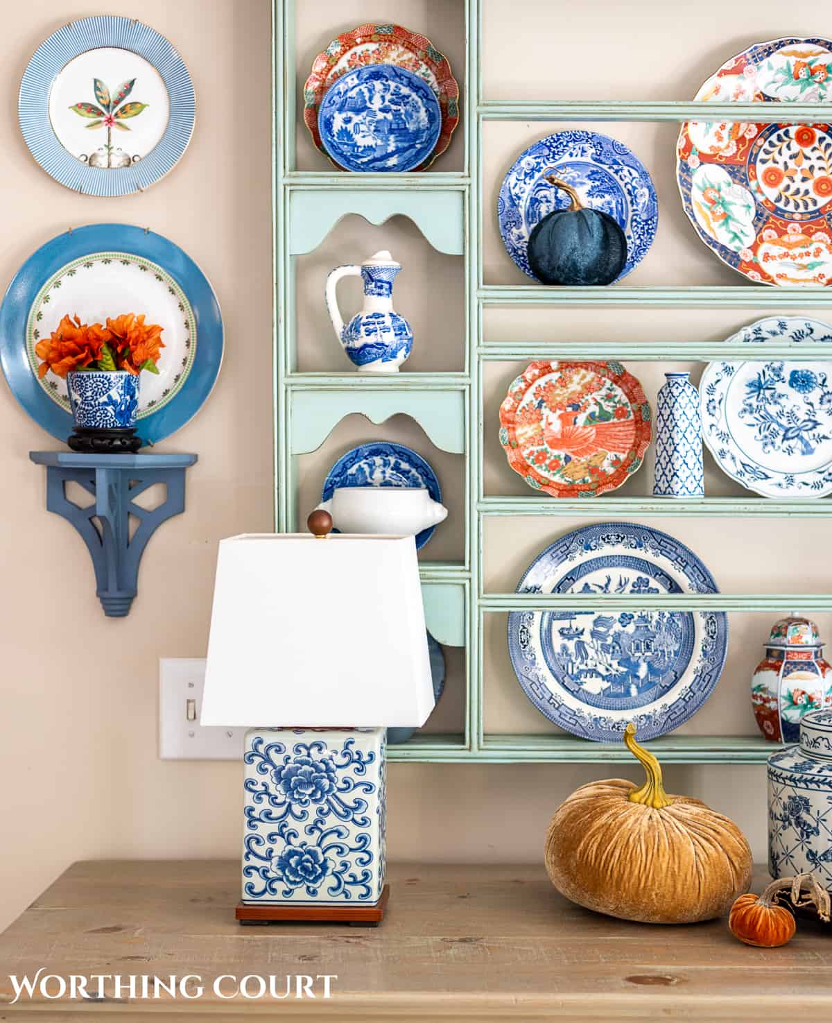 plate rack above a white sideboard filled with blue and white dishes and orange dishes for fall