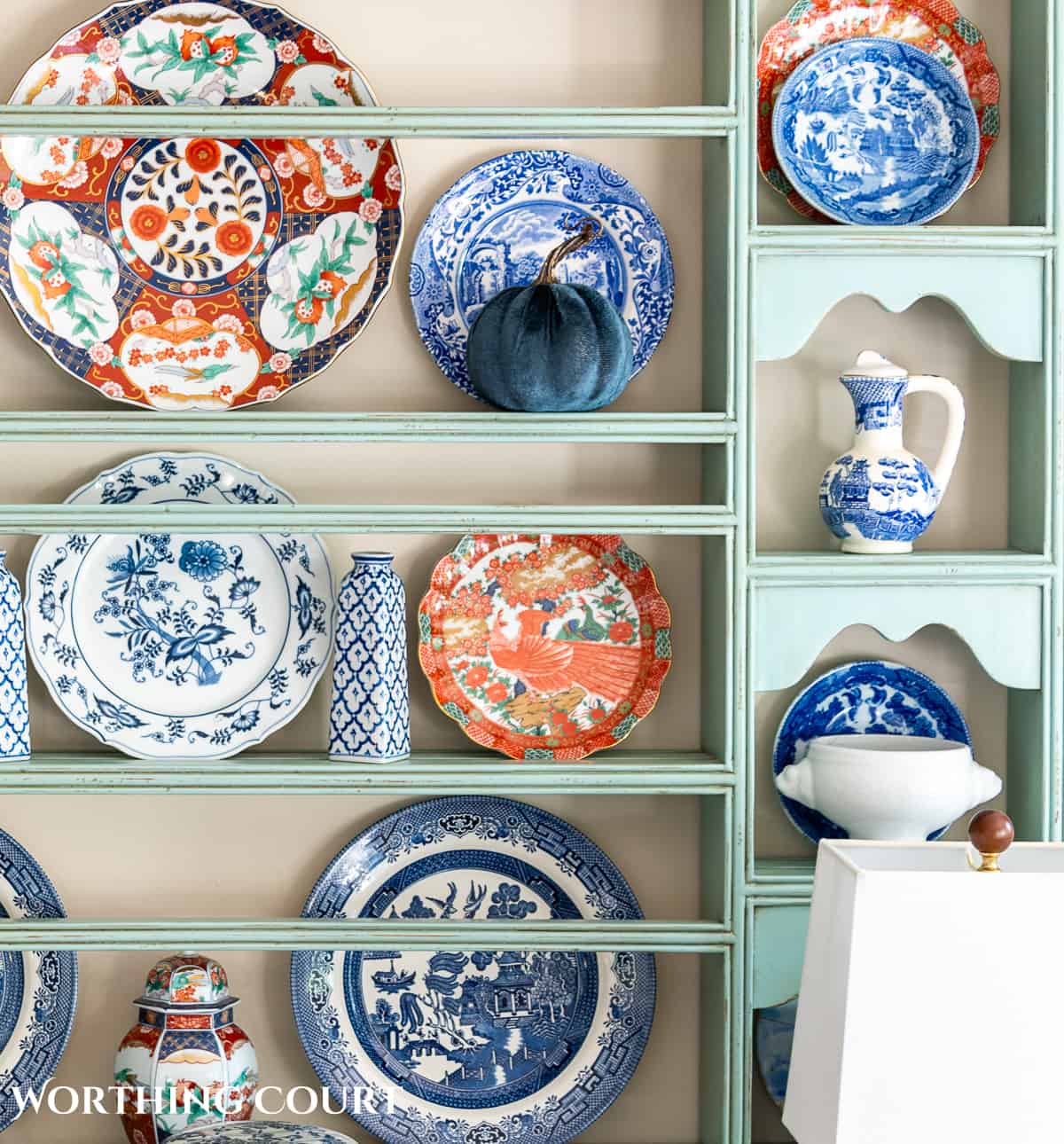 plate rack above a white sideboard filled with blue and white dishes and orange dishes for fall