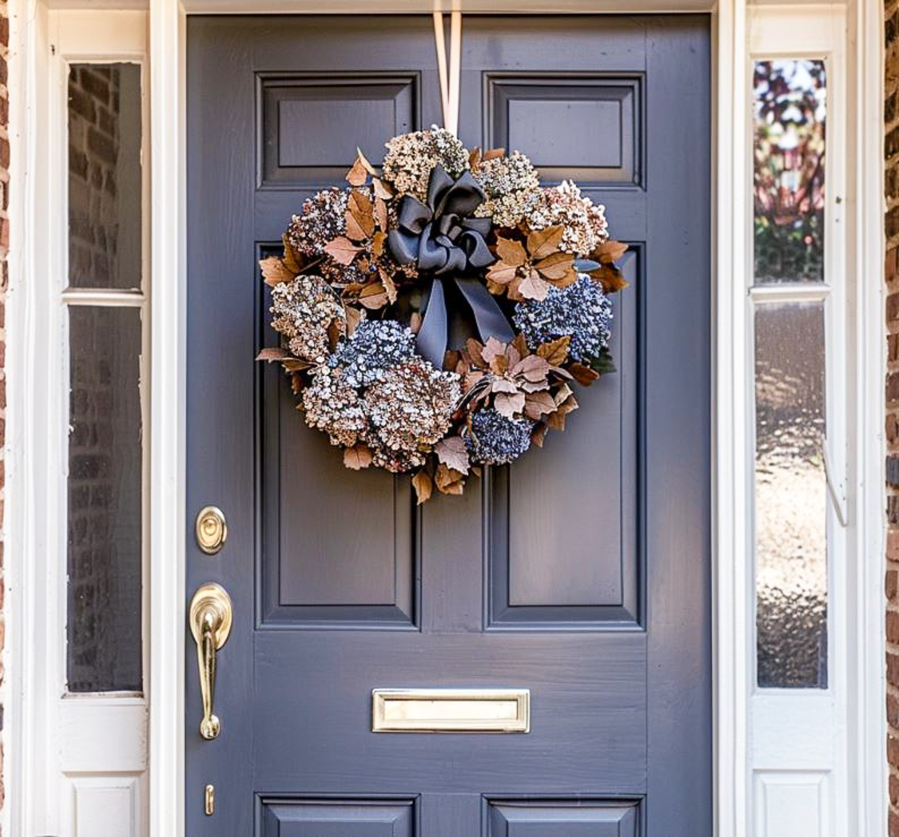 wreath made with dark blue and light blue dried hydrangeas hanging on a blue front door