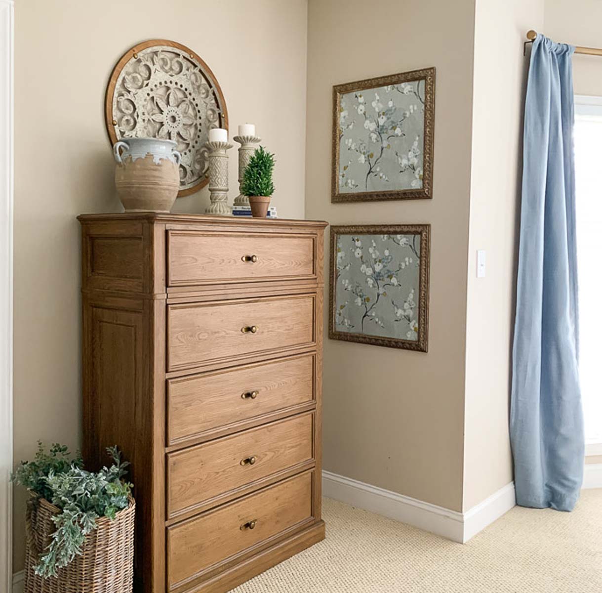 brown dresser in a bedroom with beige walls and blue curtains