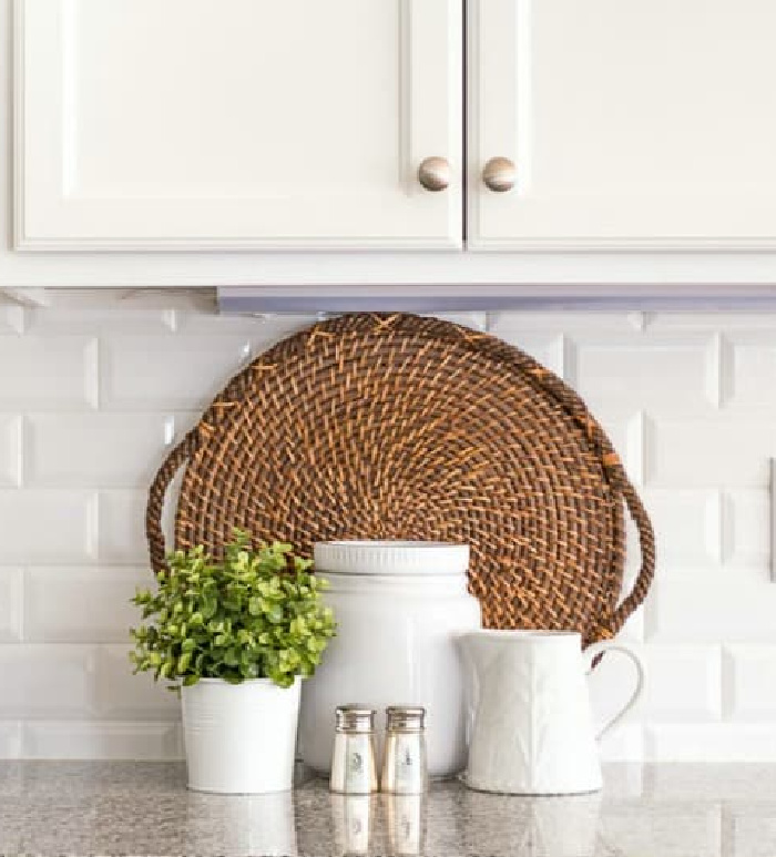 kitchen counter vignette with a round wicker tray and white accessories