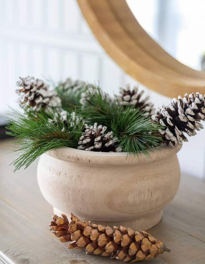 winer arrangement with pine bough stems and pine cones in a wood bowl