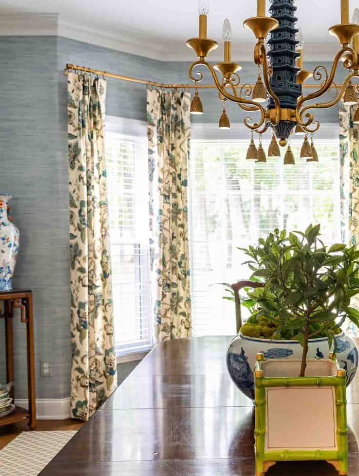 draperies hanging in a bay window in a dining room with blue wallpaper