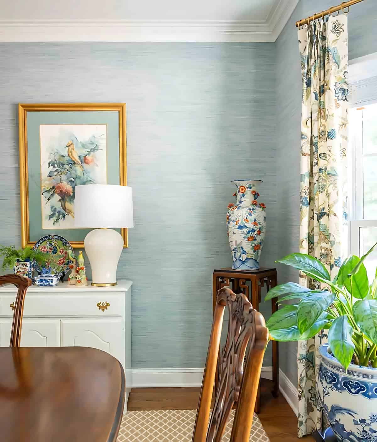 one end of a dining room with blue grasscloth wallpaper and traditional furnishings and accessories