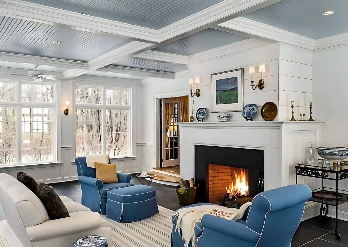 pair of blue armchairs in front of a fireplace in a living room with white furnishings