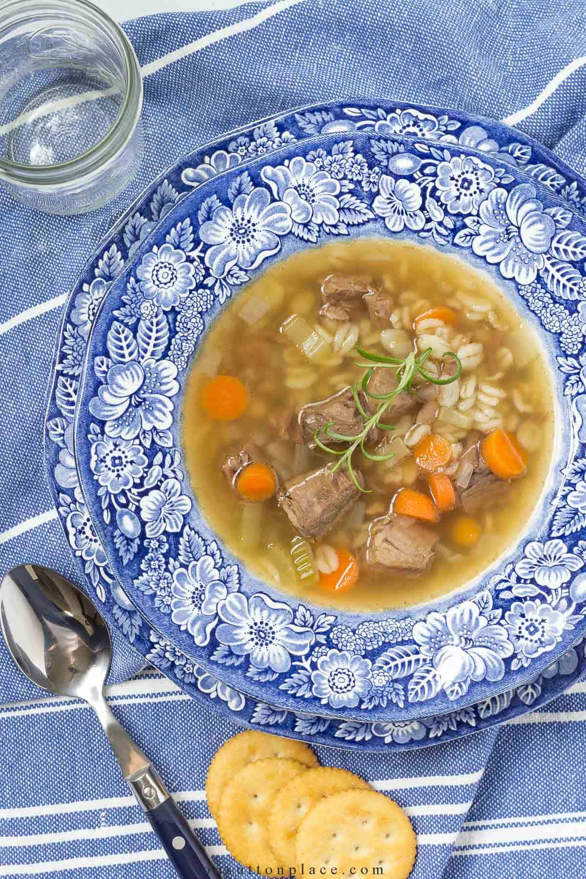 beef barley soup in a blue and white rimmed soup bowl