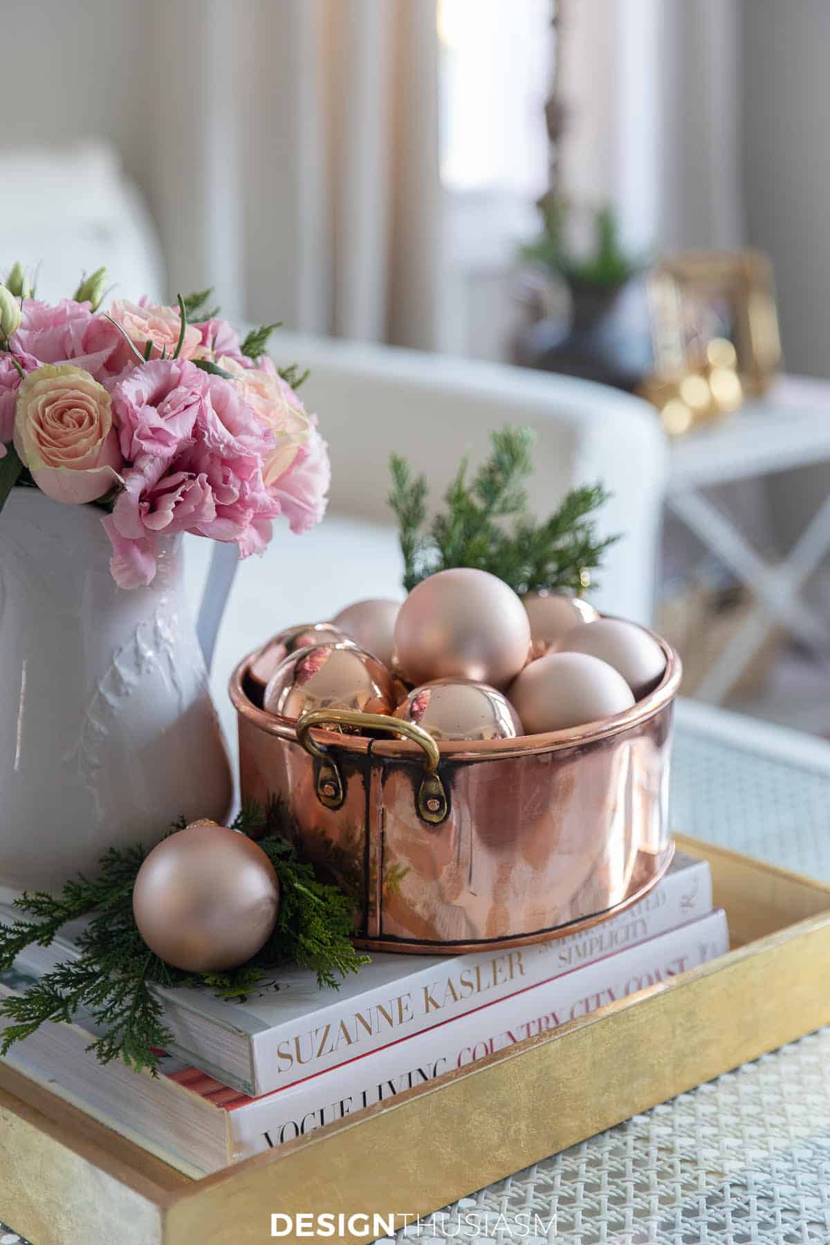 copper bowl filled with rose gold ornaments beside a vase of pink flowers