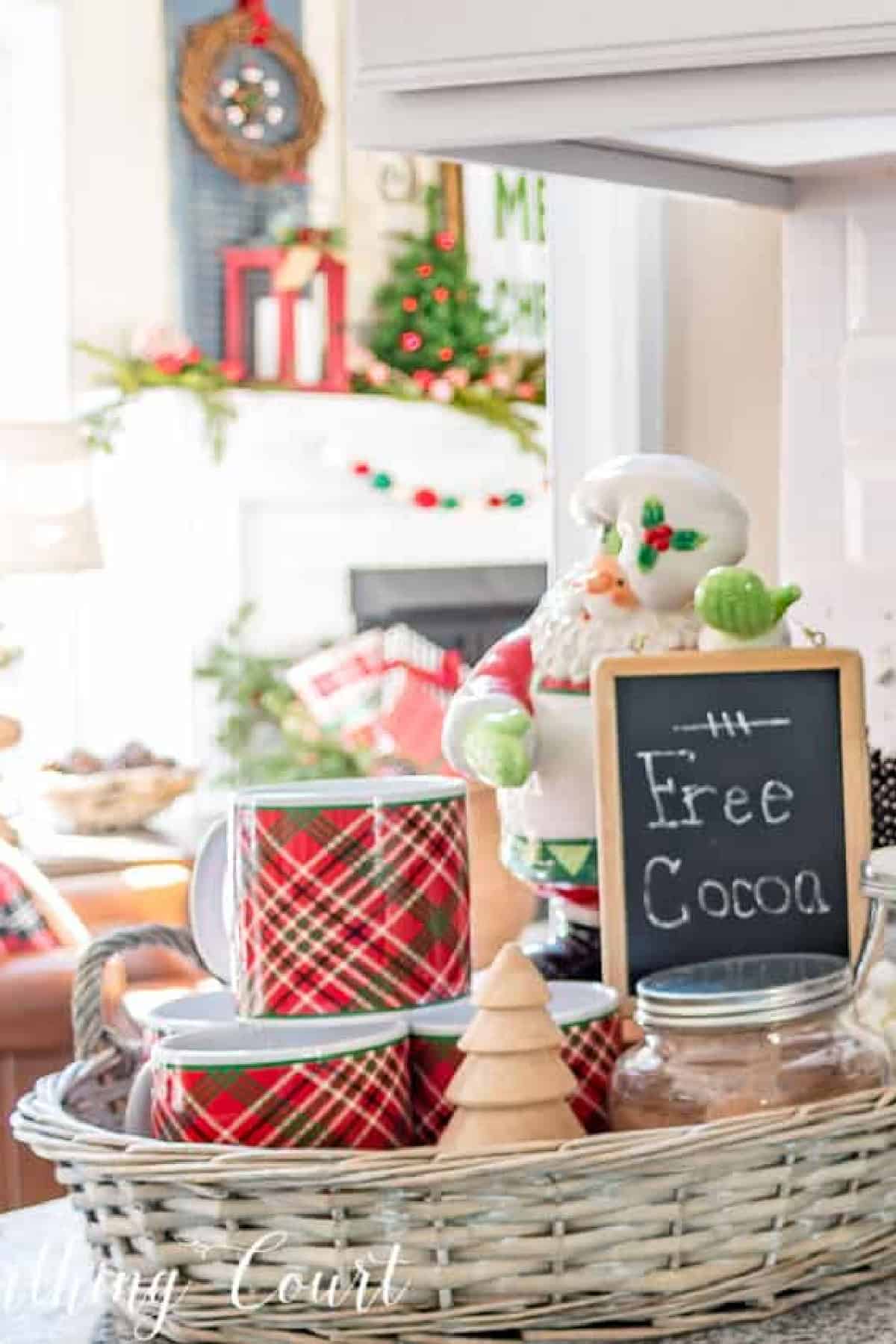 Christmas mugs next to a Santa figurine holding a chalkboard