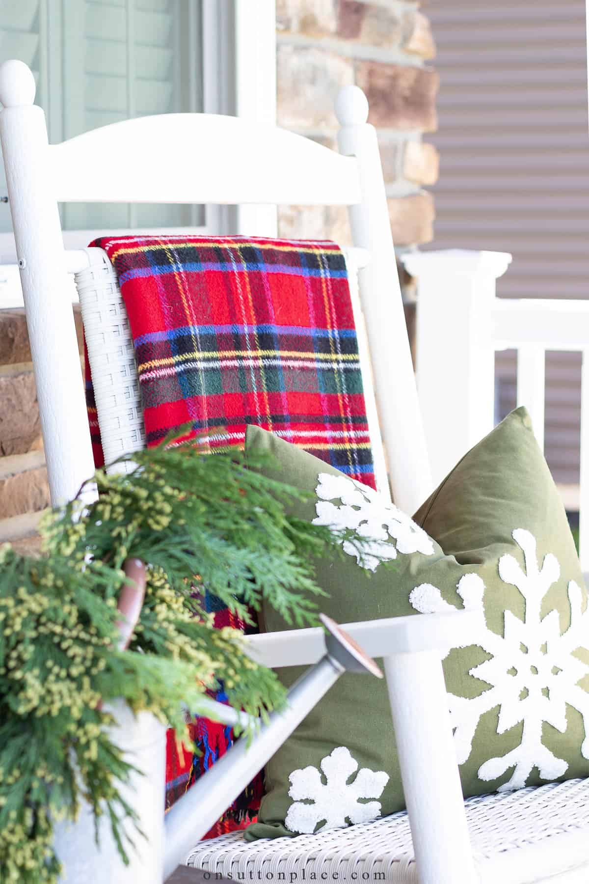 white rocking chair with a tartan plaid blanket over the back