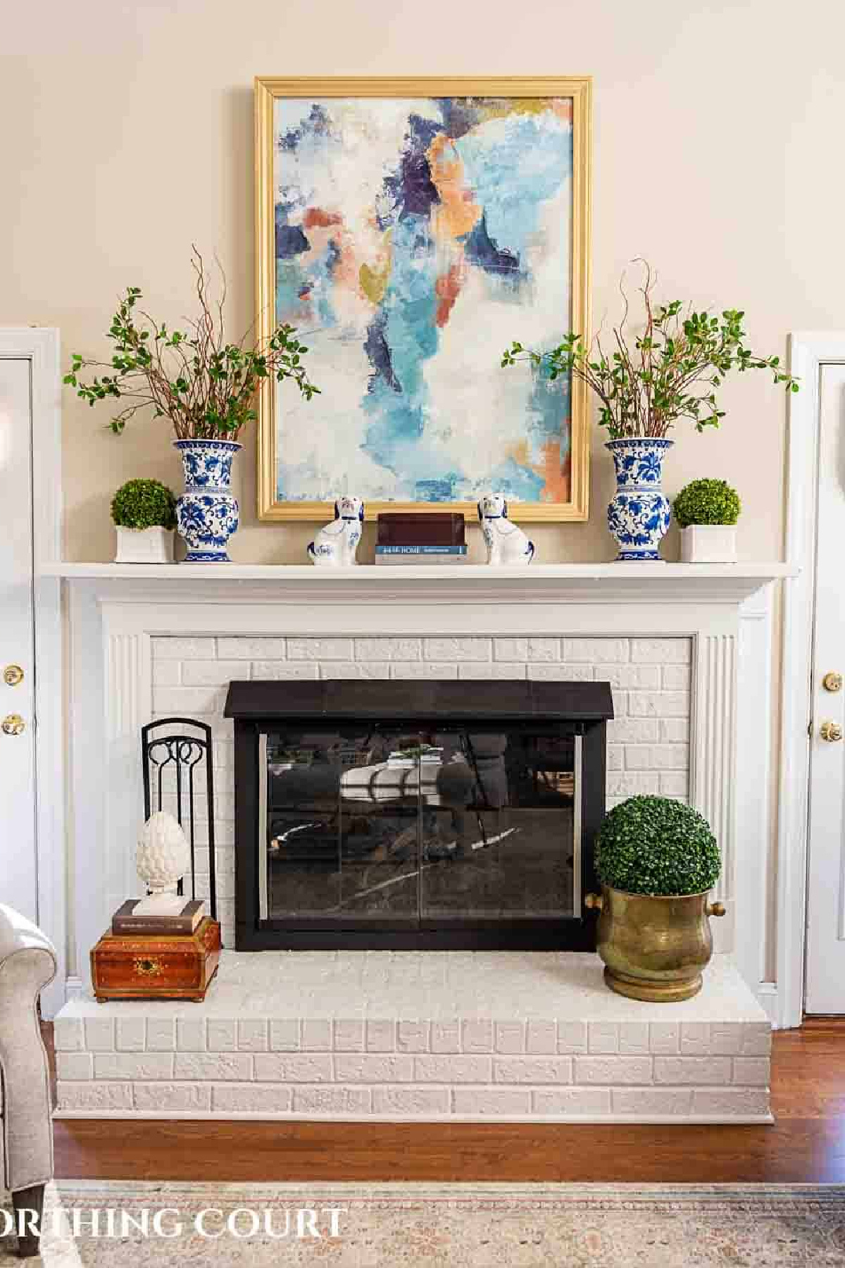 white brick fireplace and mantel with traditional accessories and abstract art