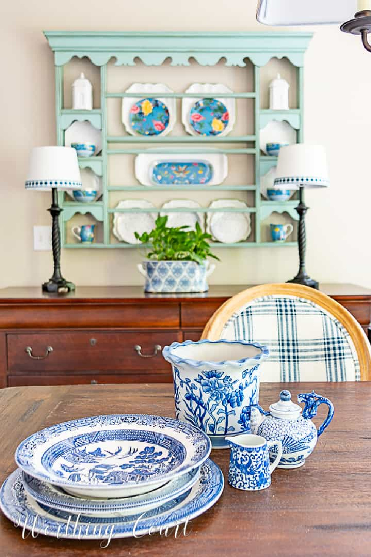 blue and white dinnerware stacked on a dining table in front of a blue plate rack