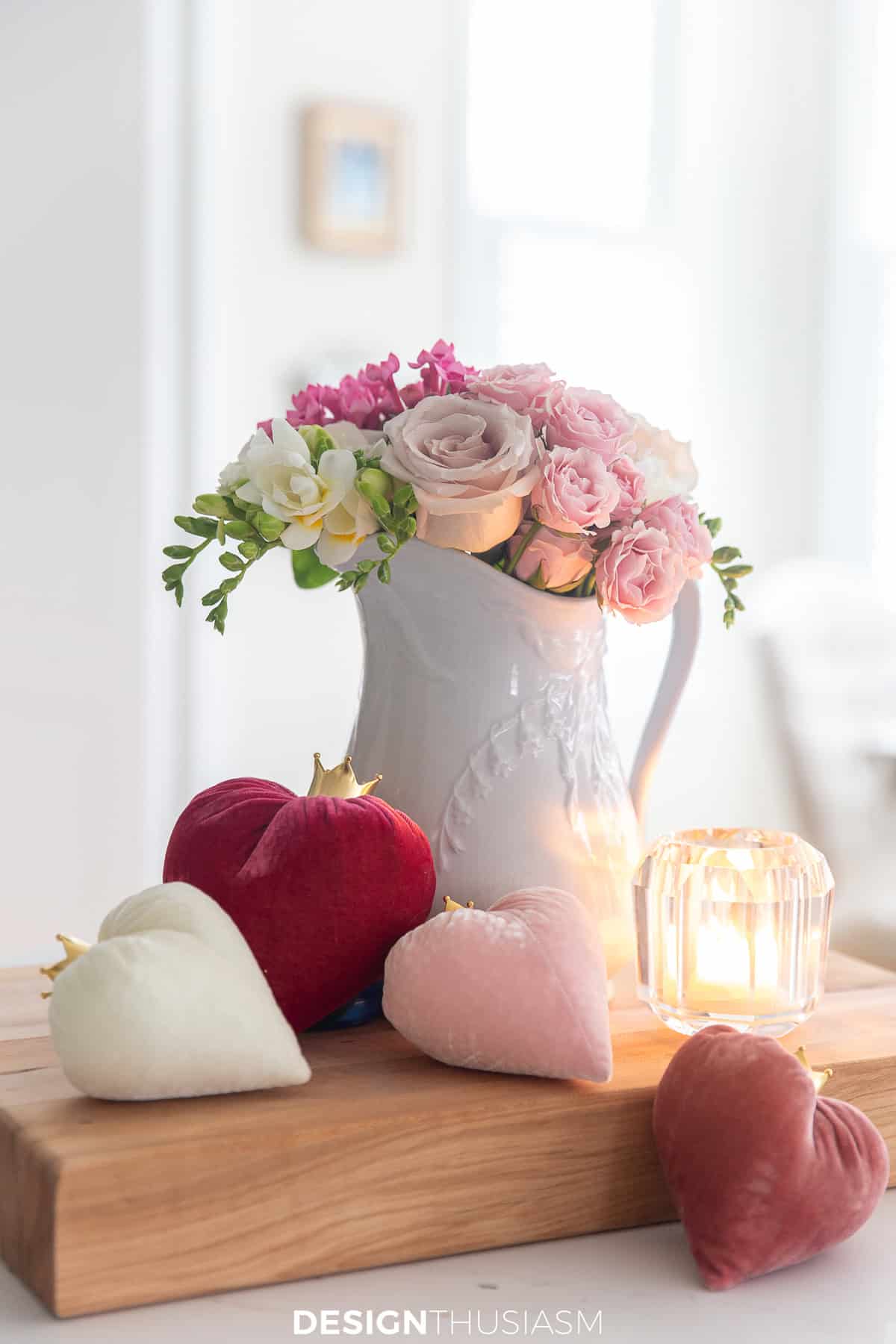 pin roses in a white pitcher beside 3 velvet hearts