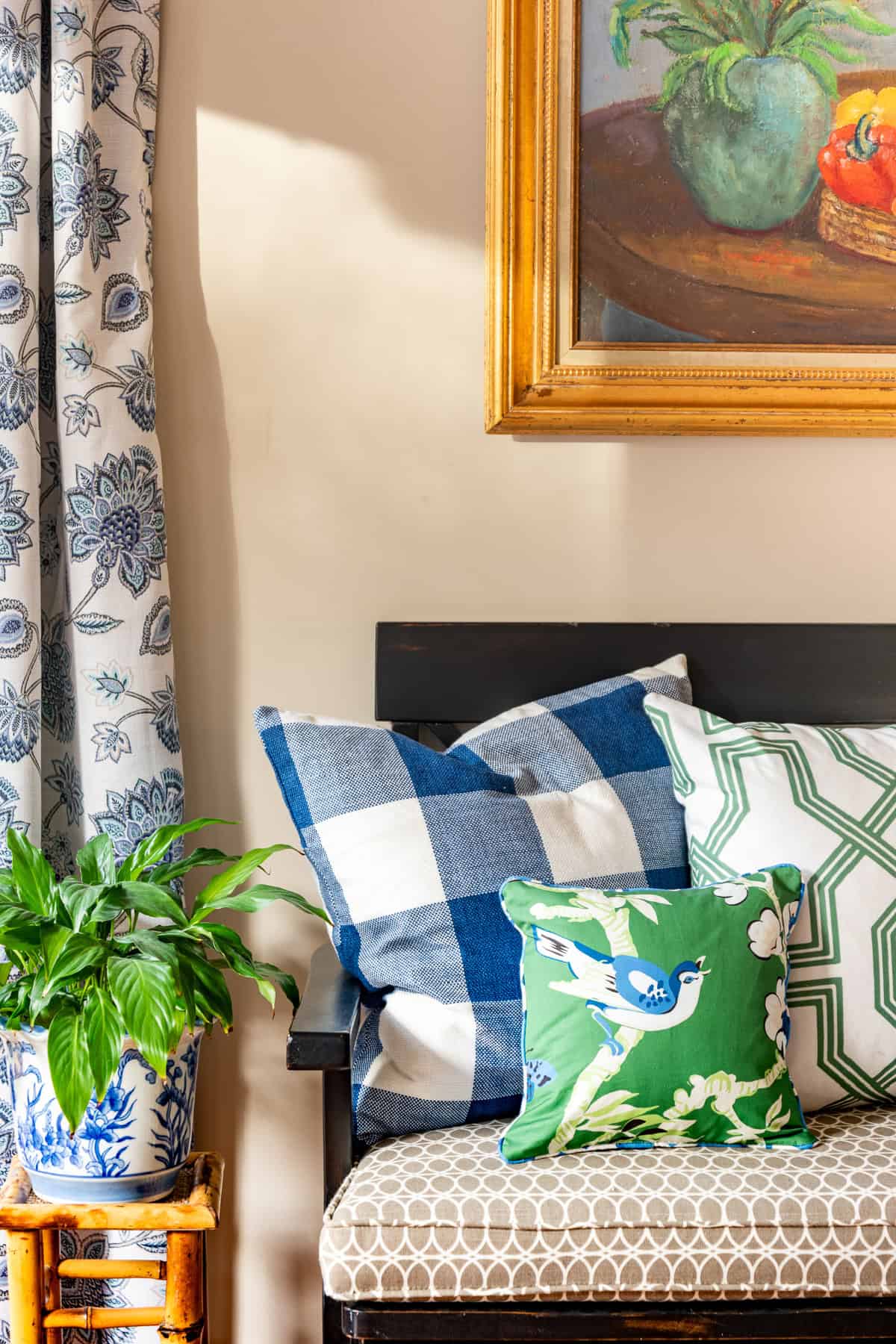 various blue, white, and green throw pillows on one end of a black bench