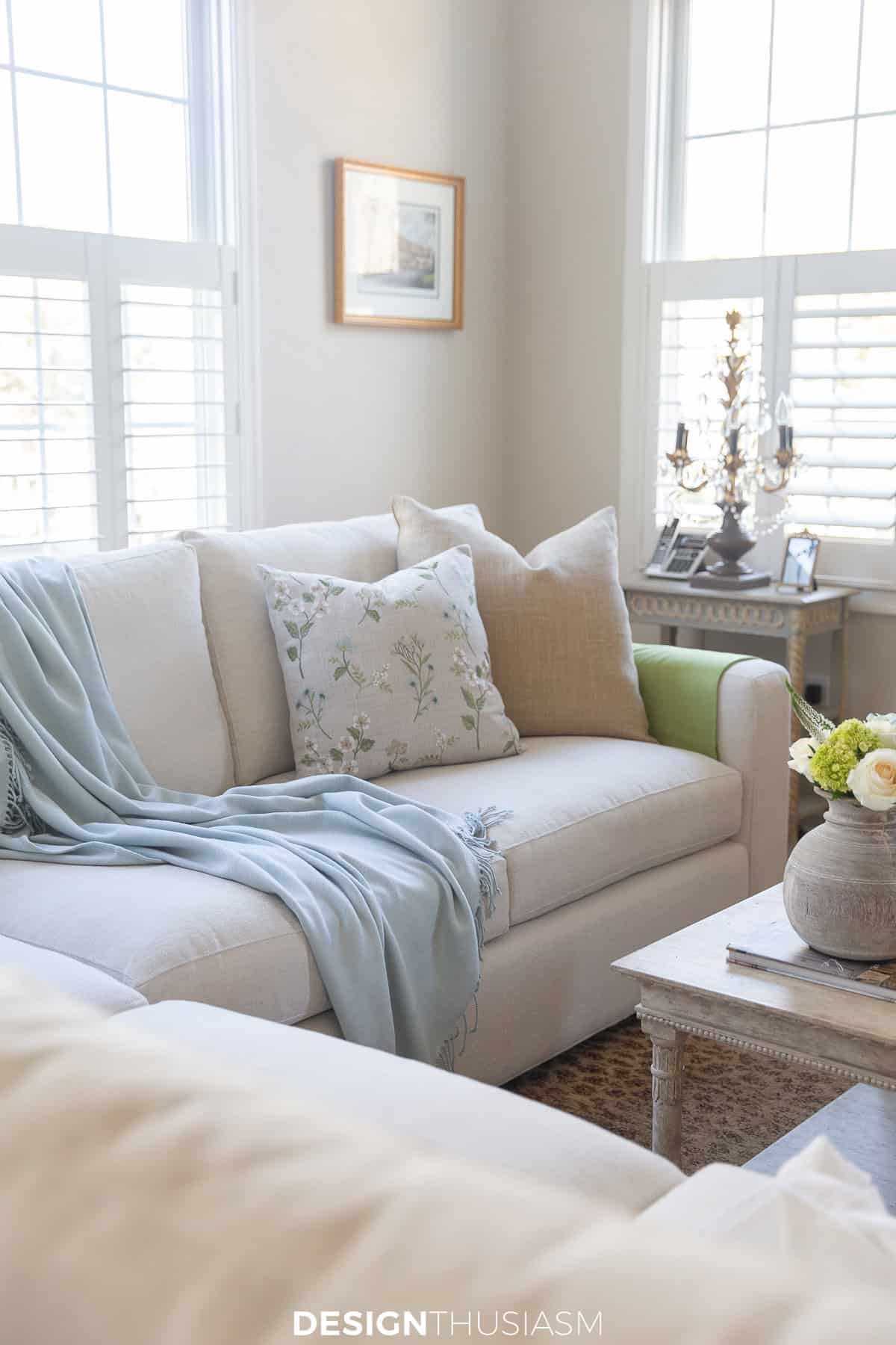 very neutrally decorated living space with sofa, shutters, and neutral furnishings