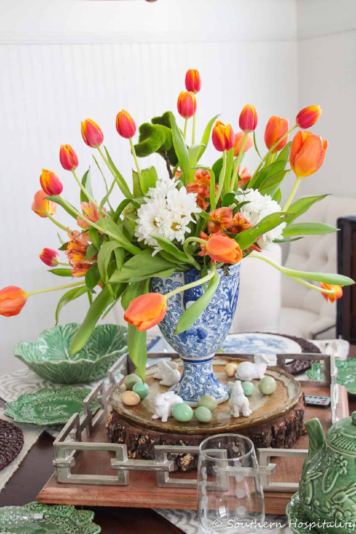 orange tulips in a blue and white vase as part of a dining table spring centerpiece