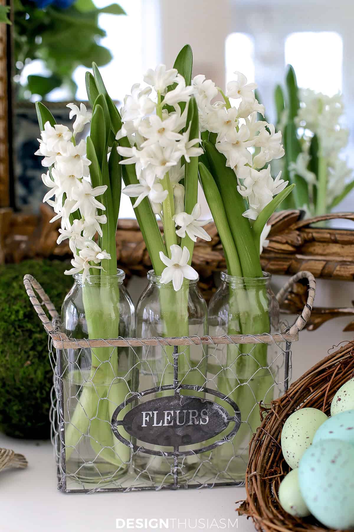 white spring flower sprigs in a trio of glass vases on a mantel