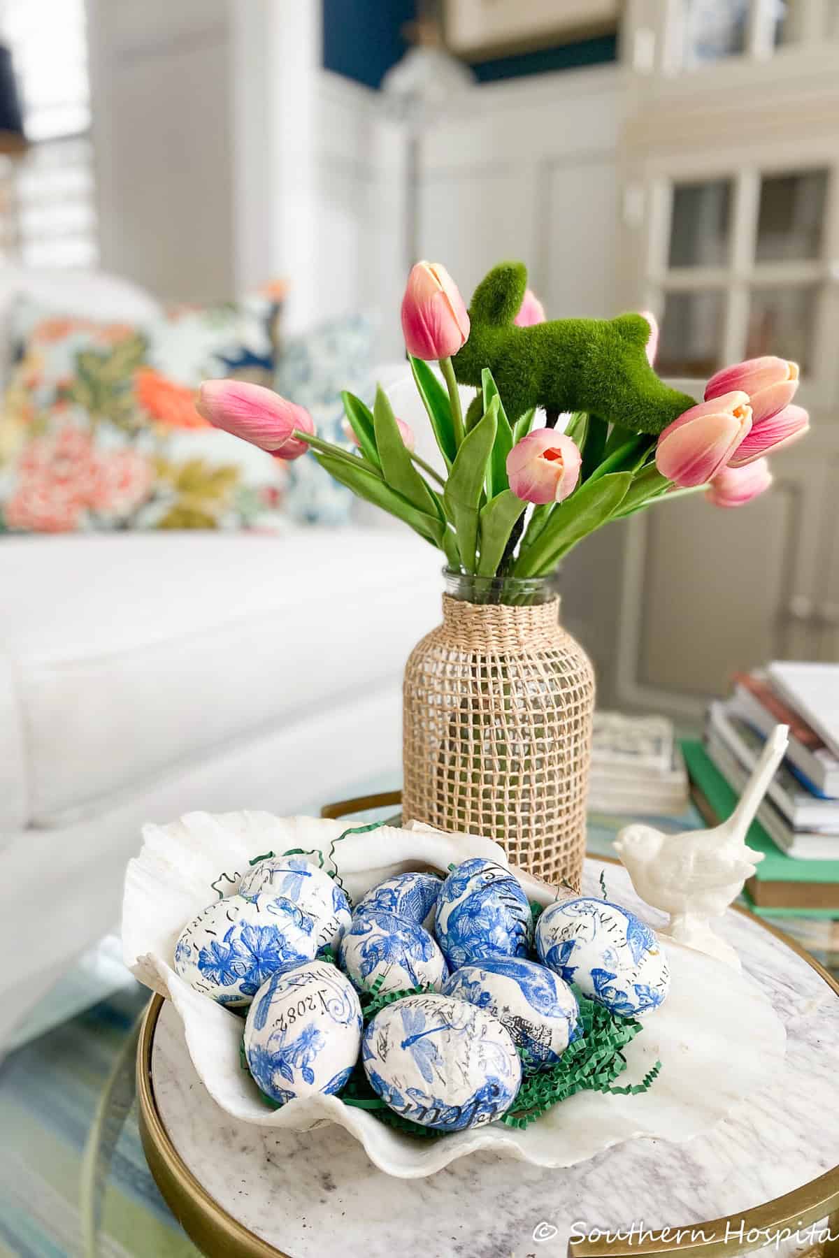 blue and white decoupaged Easter eggs displayed in a clamshell bowl on a coffee table