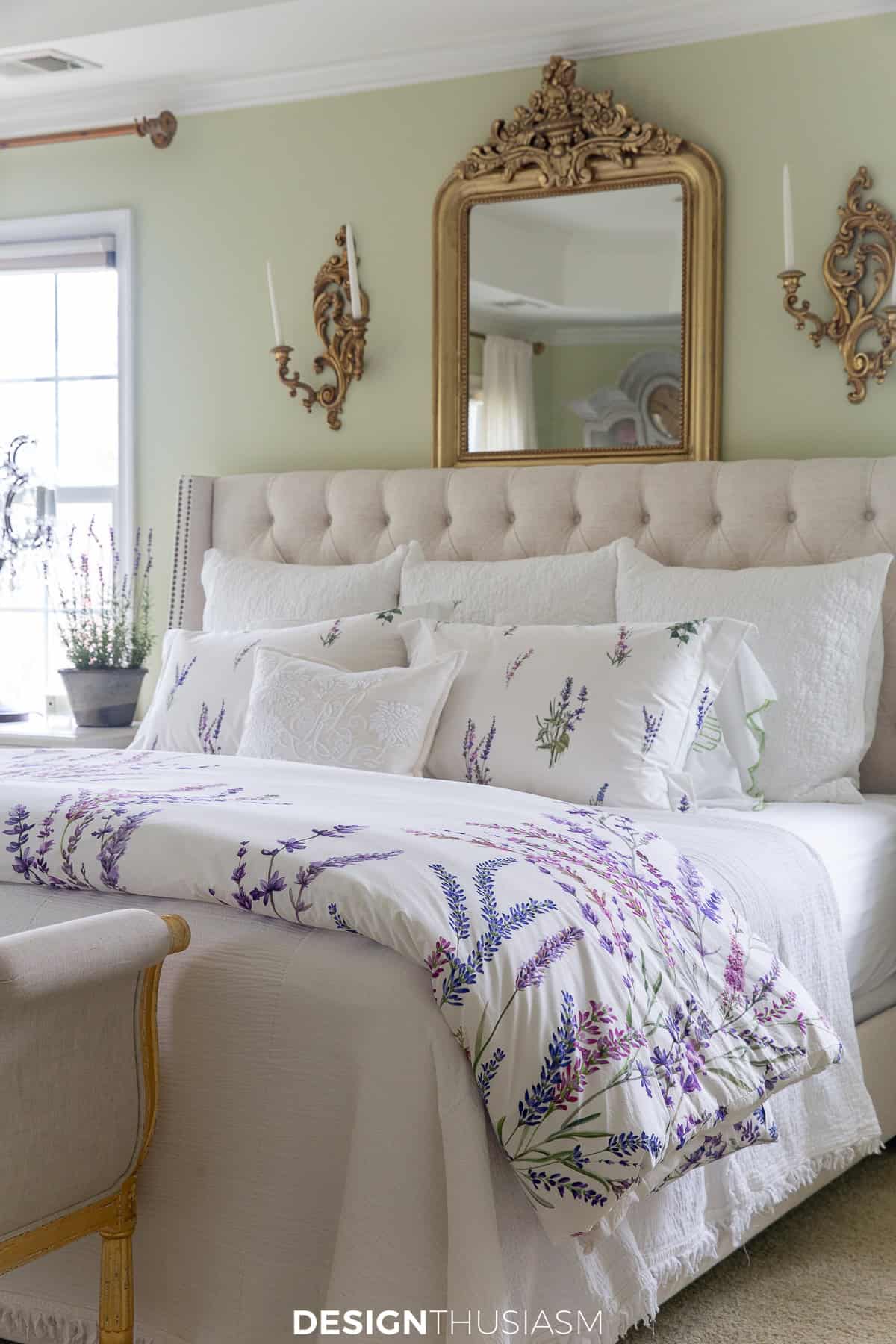 king bed with a white tufted headboard and french style wall accessories and bedding