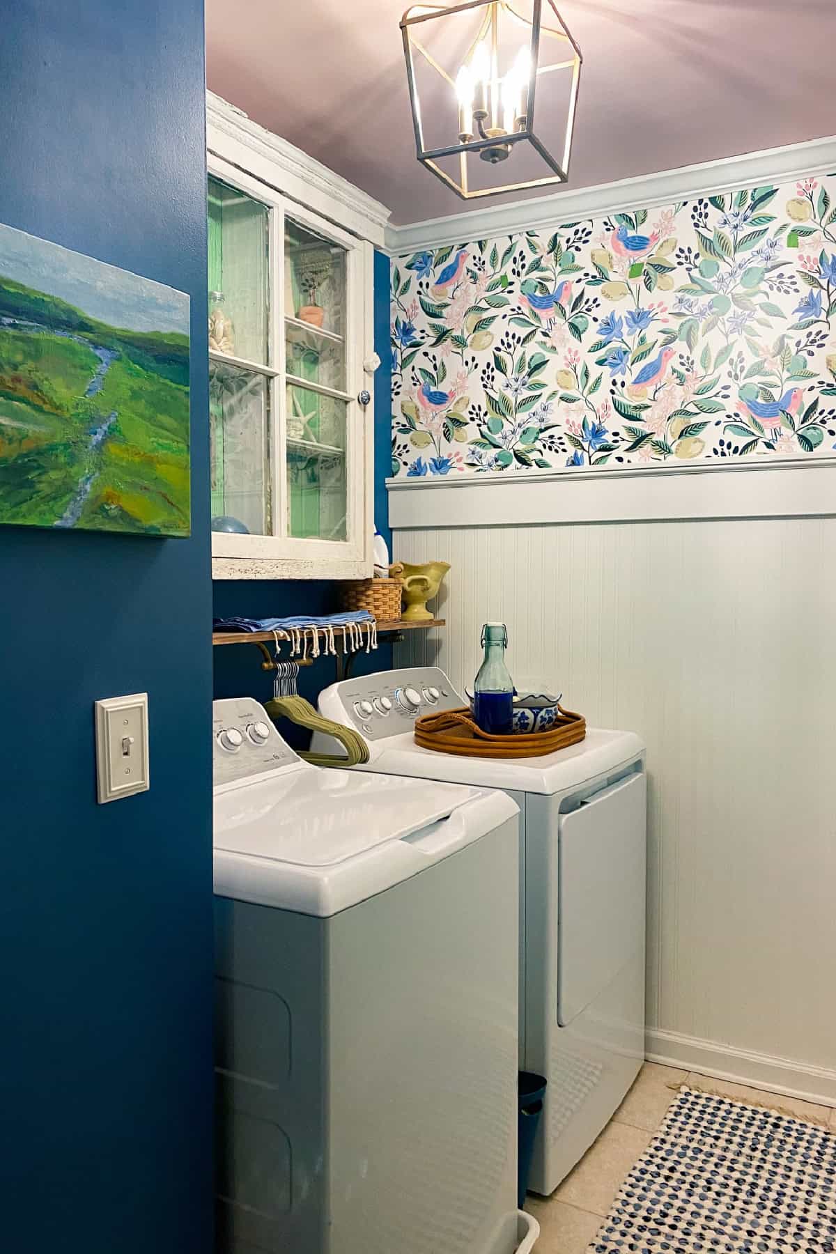 laundry room with colorful wallpaper, blue paint, and vintage decor