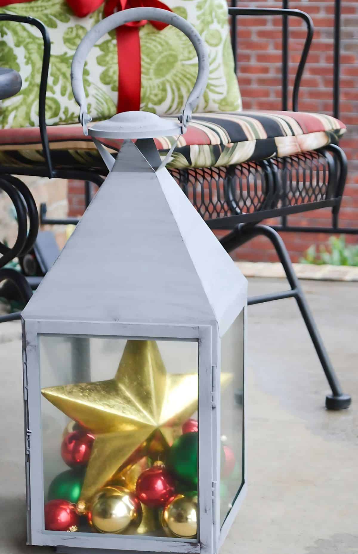 large lantern filled with ornaments and a tree topper star