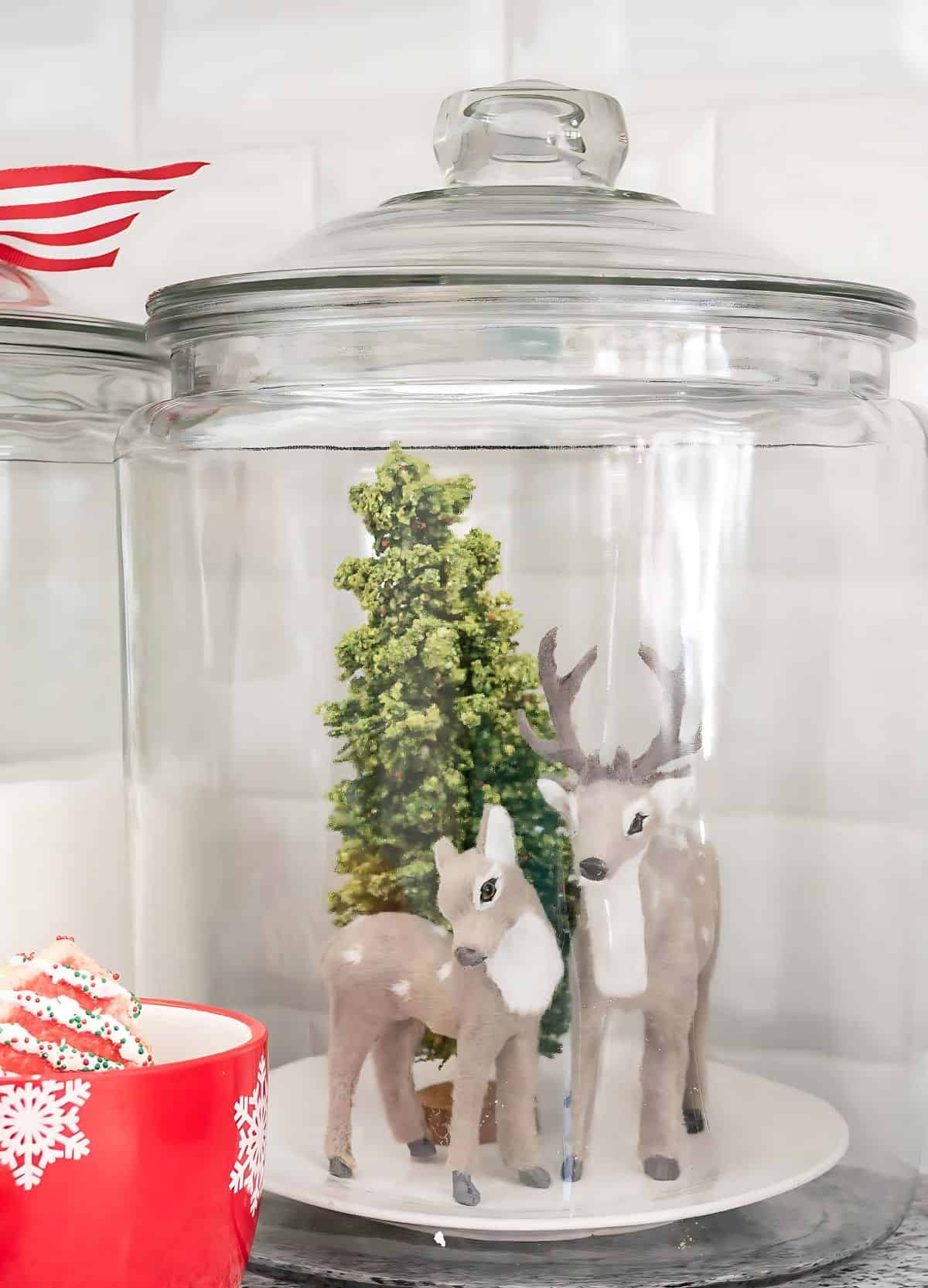 glass canister with two deer and mini Christmas tree inside