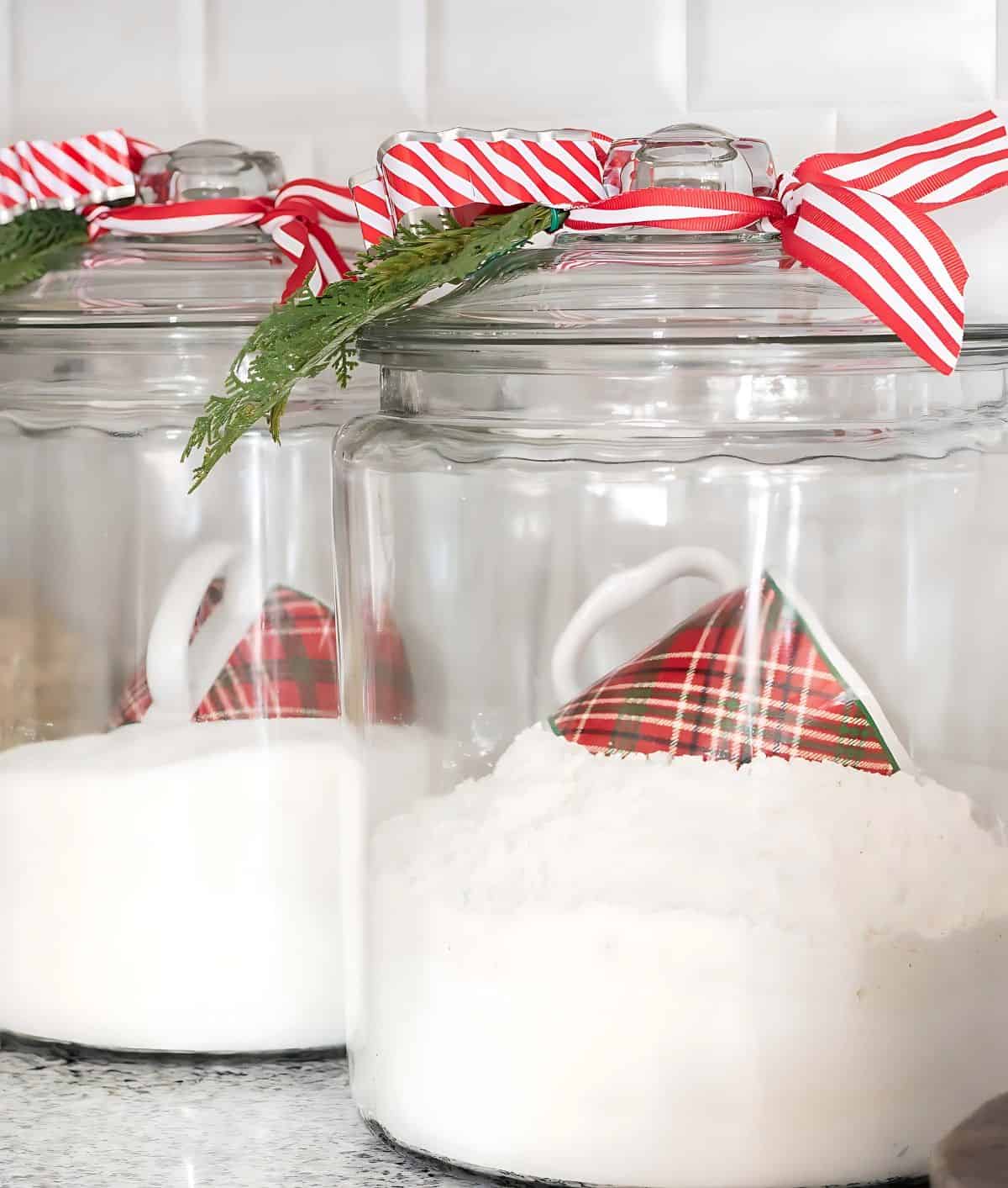 glass canisters filled with flour and sugar with Christmas mugs for scoops