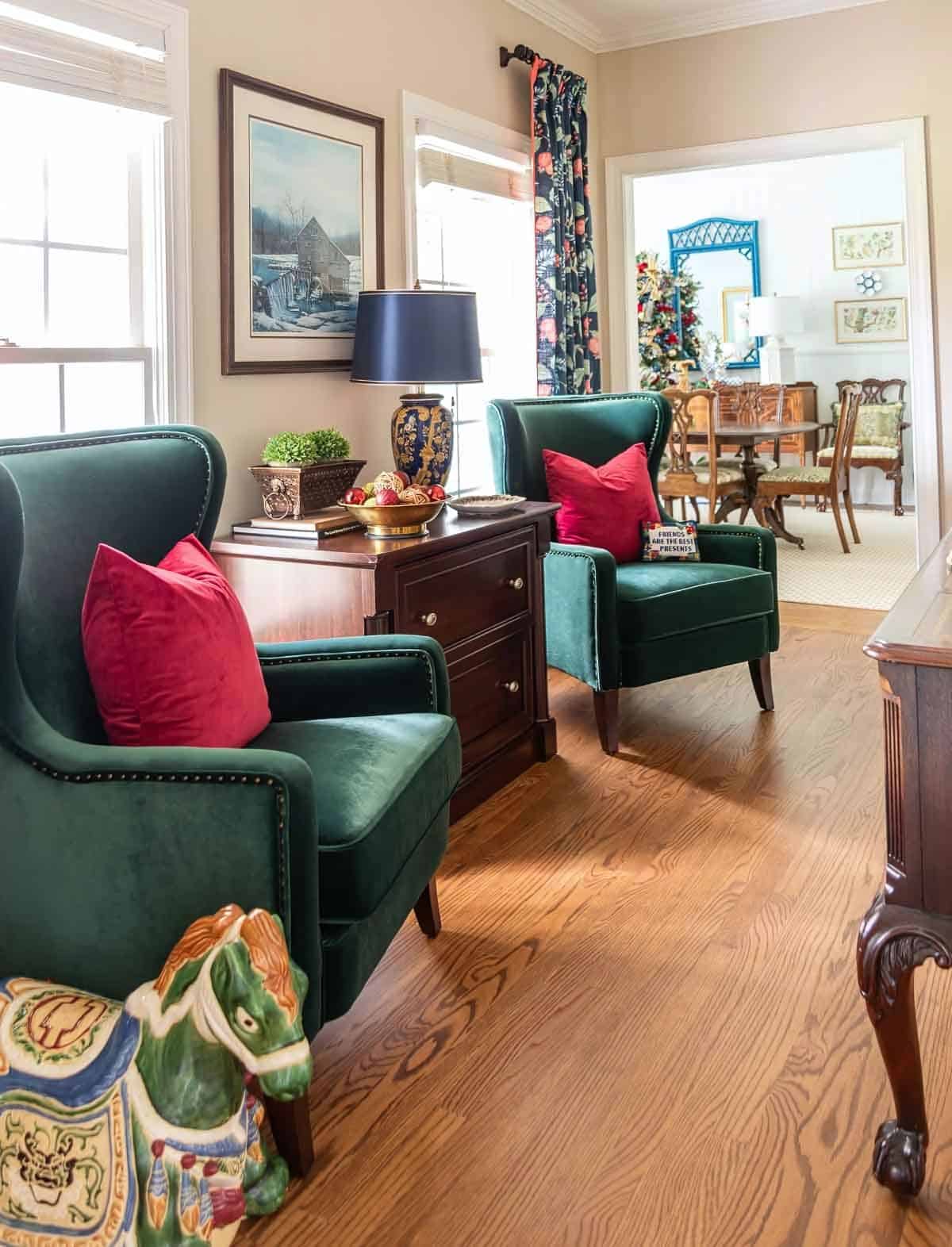 pair of green velvet chairs flanking a wood lateral file cabinet