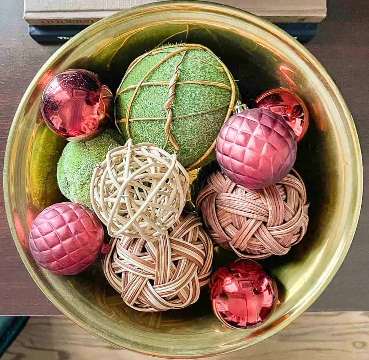 brass bowl filled with moss orbs and burgundy Christmas ornaments