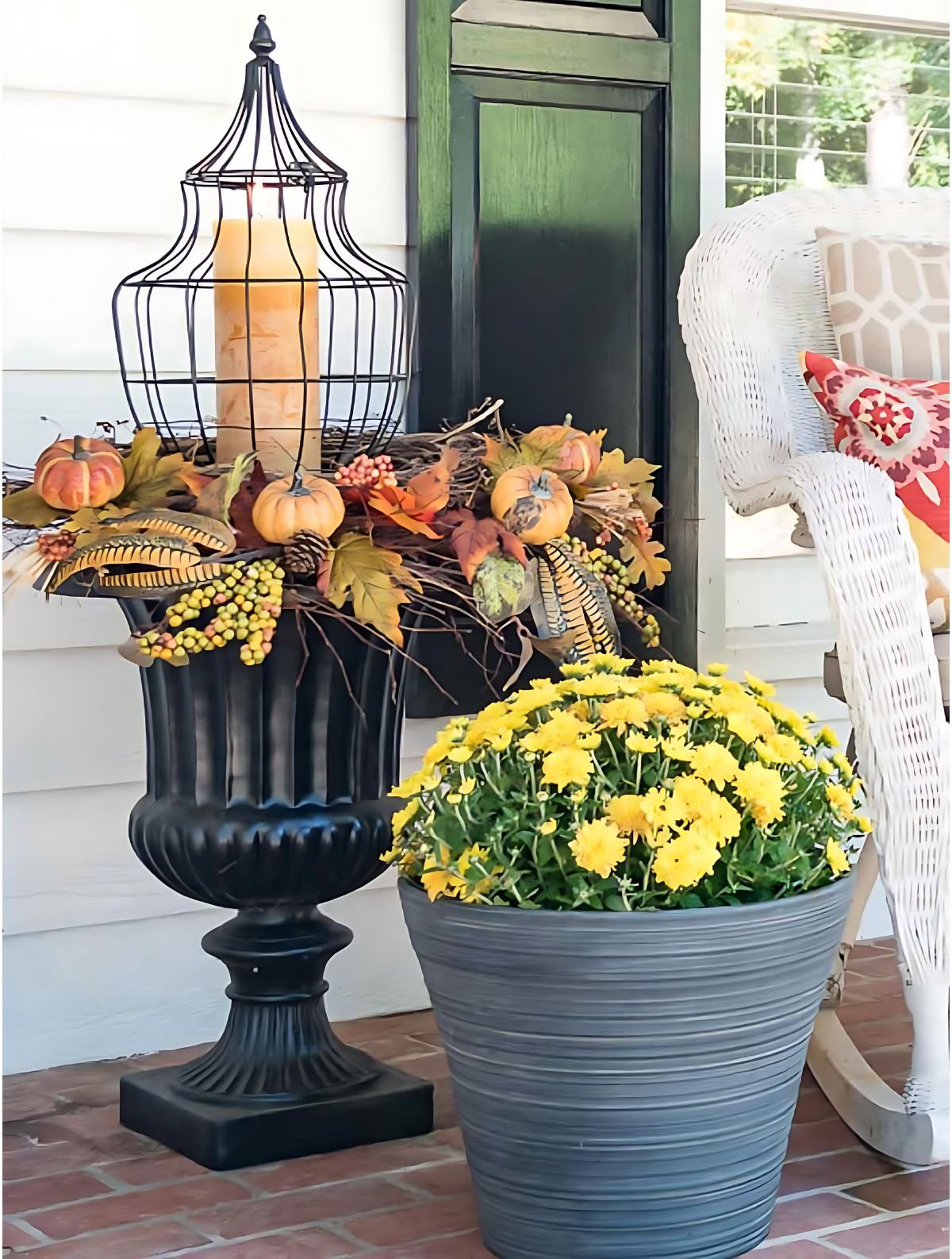 fall arrangement in a black urn with a tall lantern and candle in the center, filled in with fall-themed picks around the rim of the planter