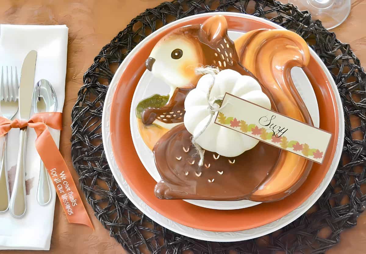 Thanksgiving place setting of stacked plates with a squirrel accent plate on top