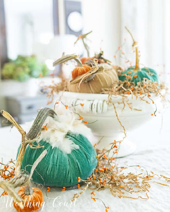 large white pedestal bowl filled with velvet pumpkins in various colors