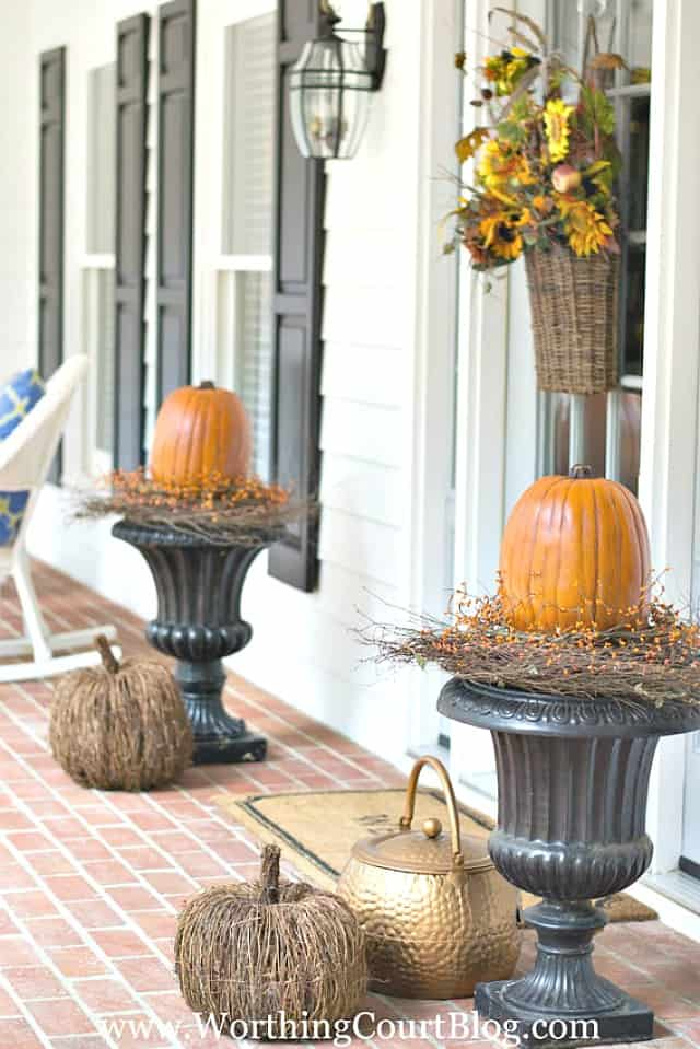 black urns with large pumpkins in them flanking a front door