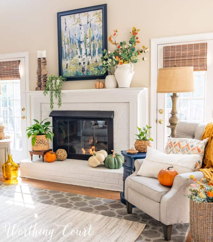 white brick fireplace decorated for fall with a neutral recliner beside it