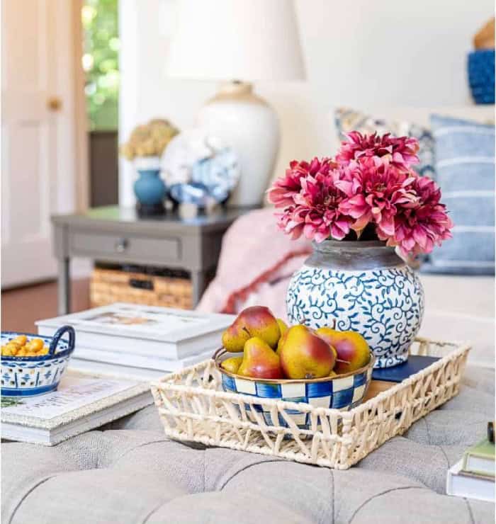 fall vignette with burgundy mums in a blue and white vase on an upholstered coffee table