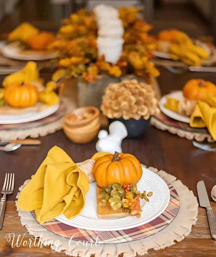 Thanksgivng place setting with a burlap placemat, plaid charger and white dinner plate