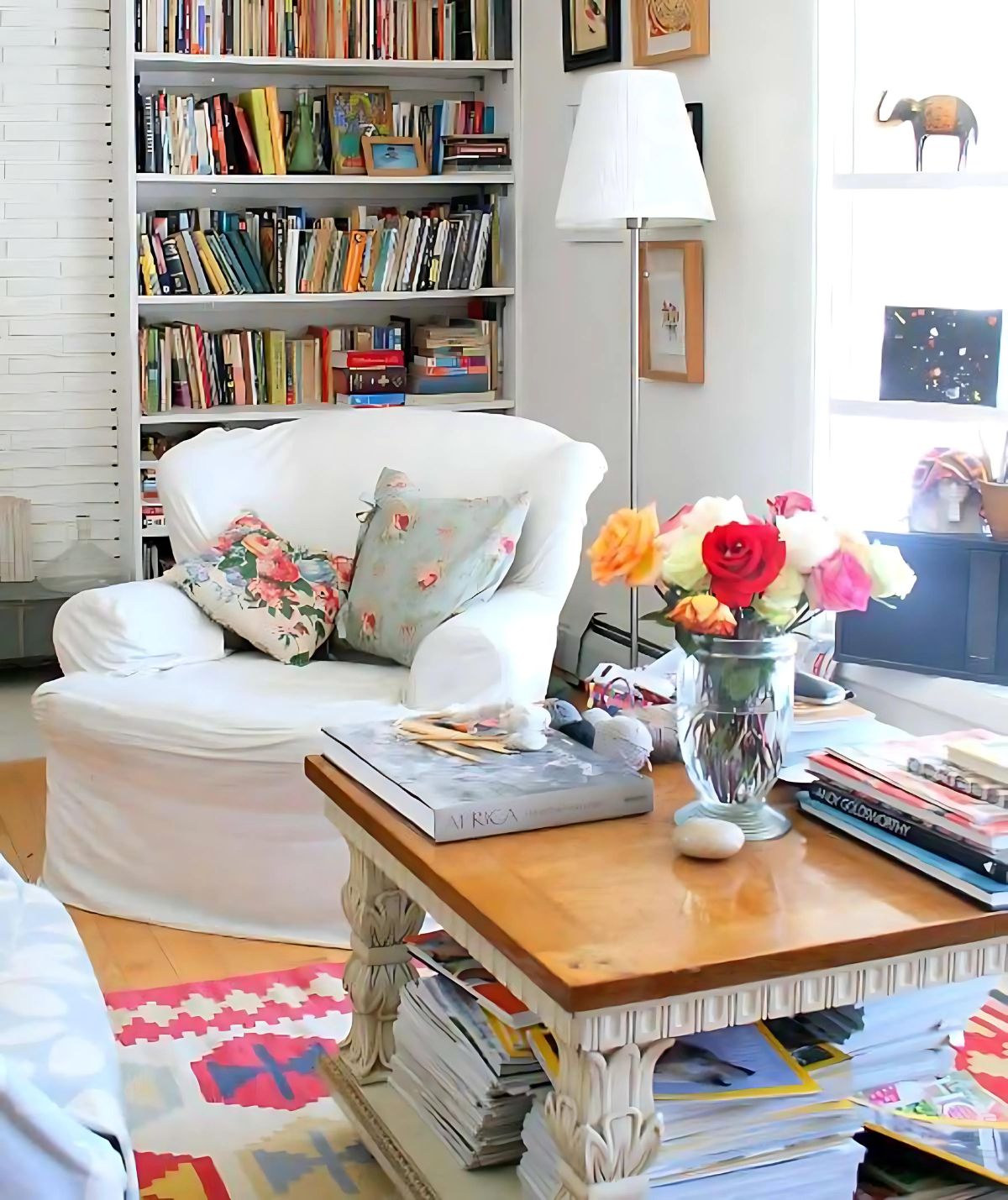 cozy cottage style living room with white slipcovered chair and lots of books