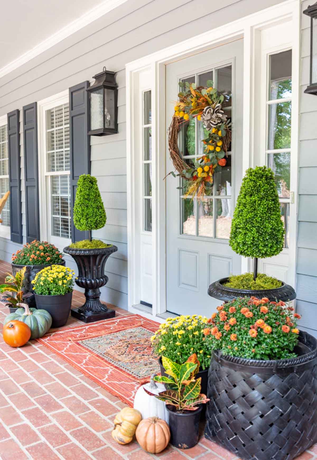 front porch decorated for fall with a variety of pumpkins and mums