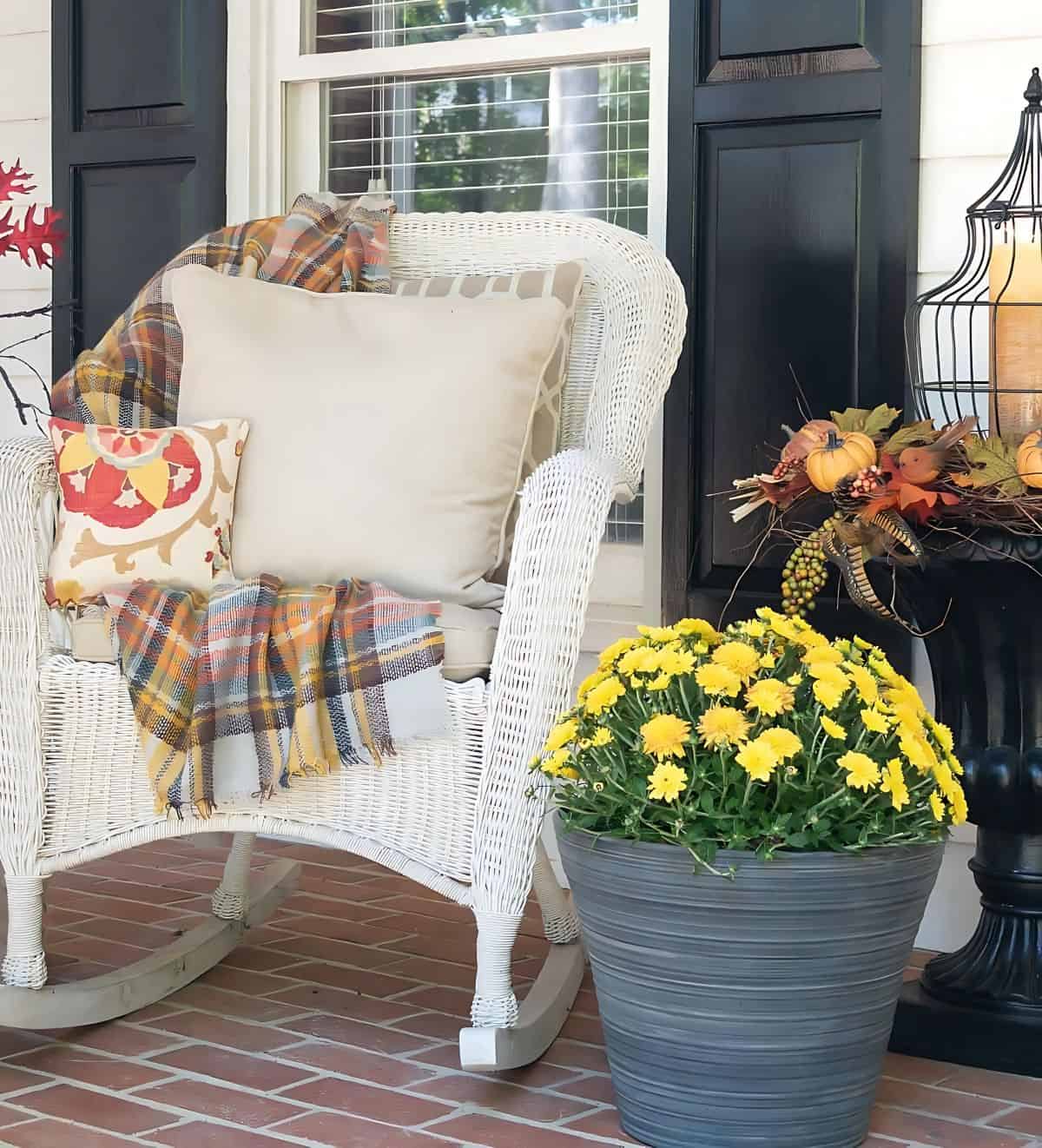 white wicker rocking chair with fall pillows and a plaid fall throw blanket