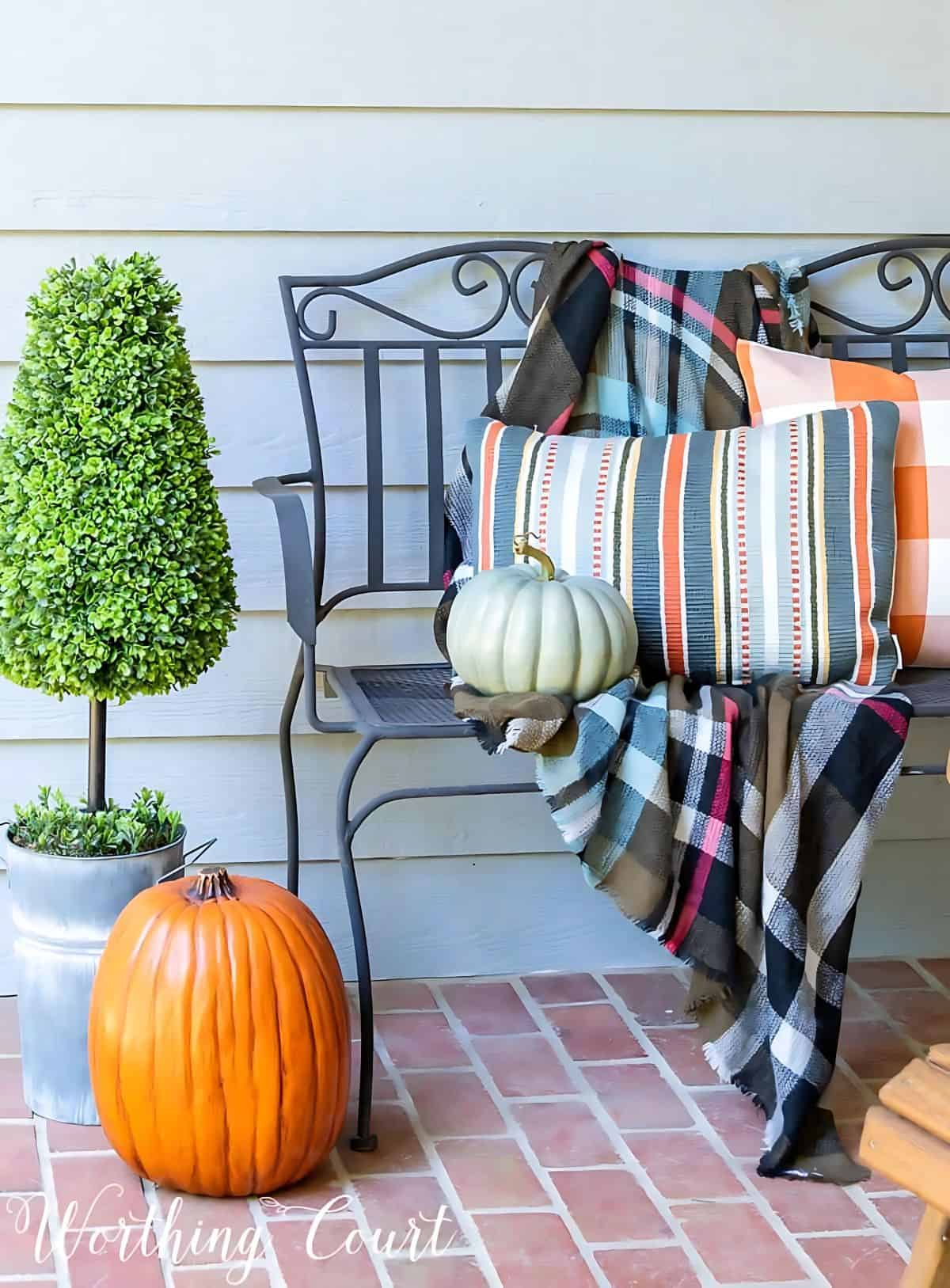 black metal bench with fall pillows and plaid throw blanket