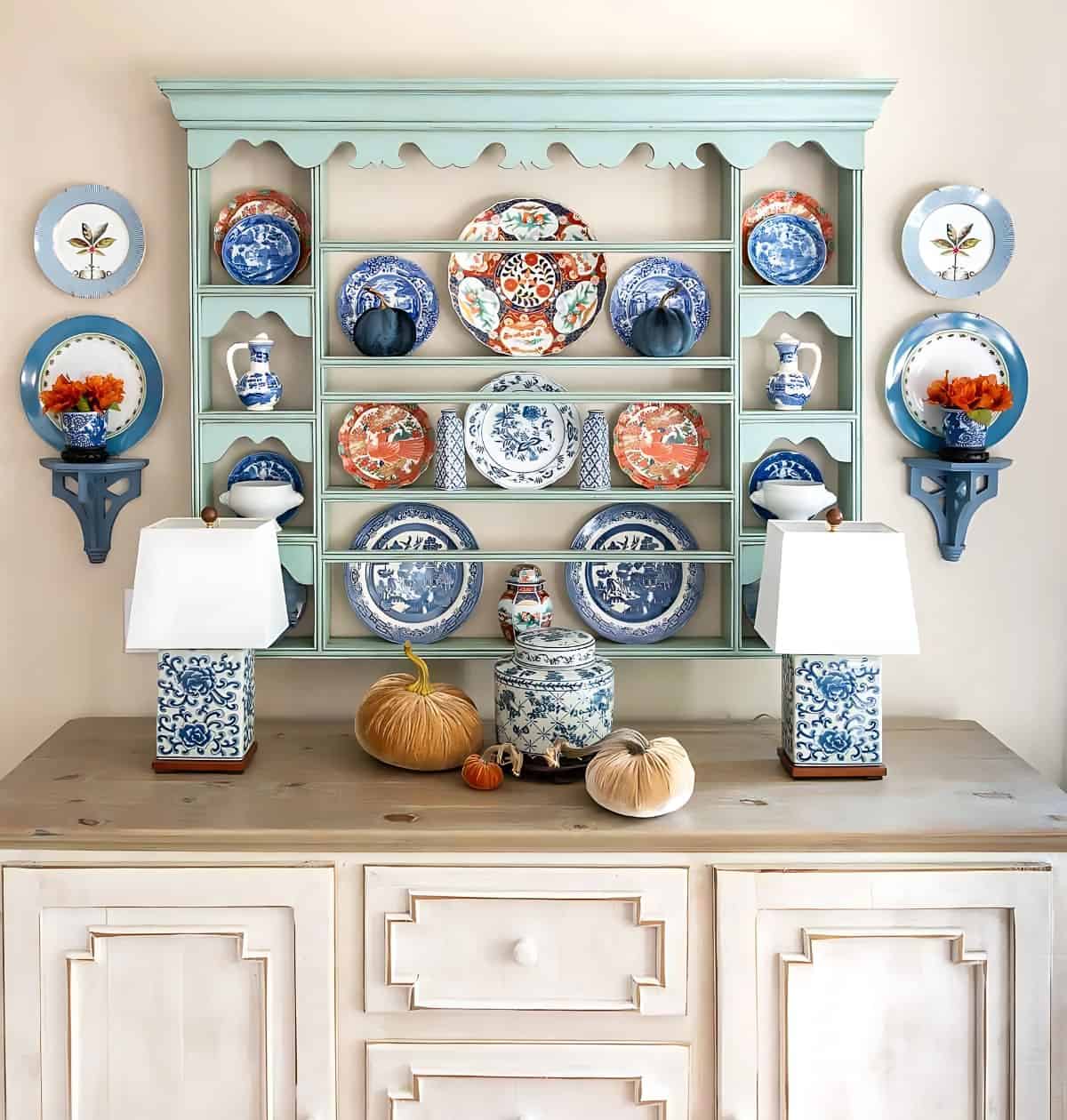 blue plate rack above a white sideboard decorated with blue and orange plates for fall